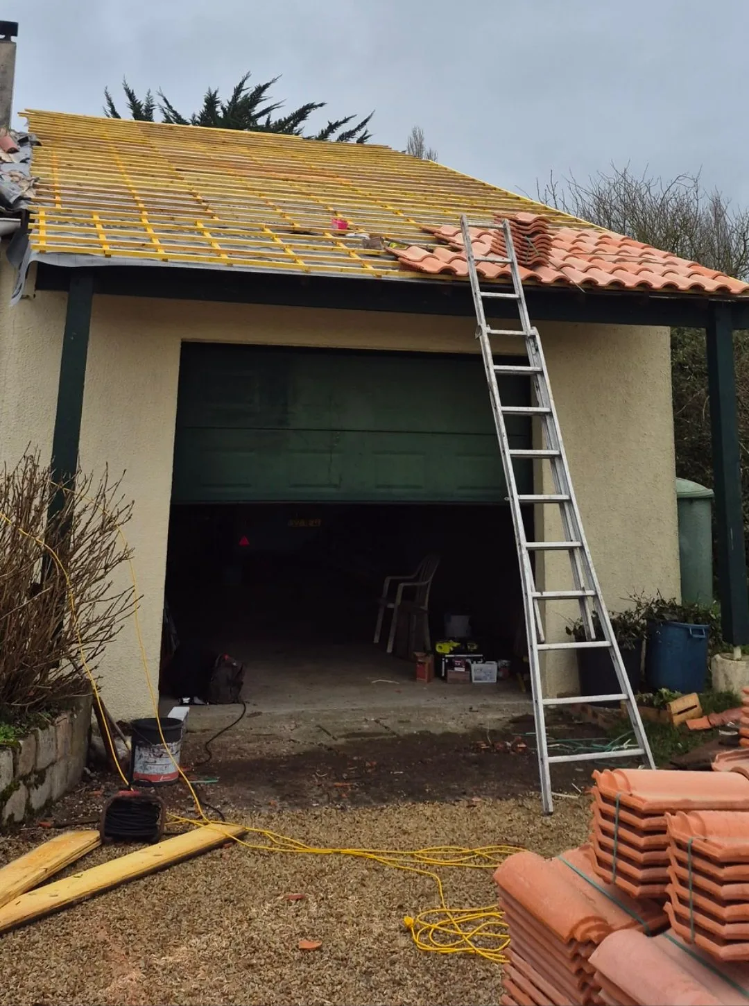 Couverture en tuiles en cours de rénovation, l'échelle posée et les tuiles neuves au pied