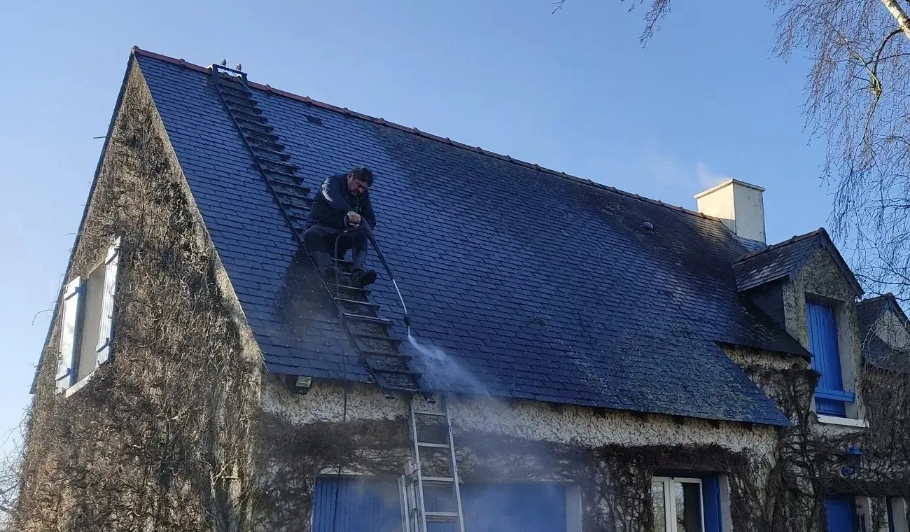 Samuel Martin sur un toit en ardoise, en plein démoussage